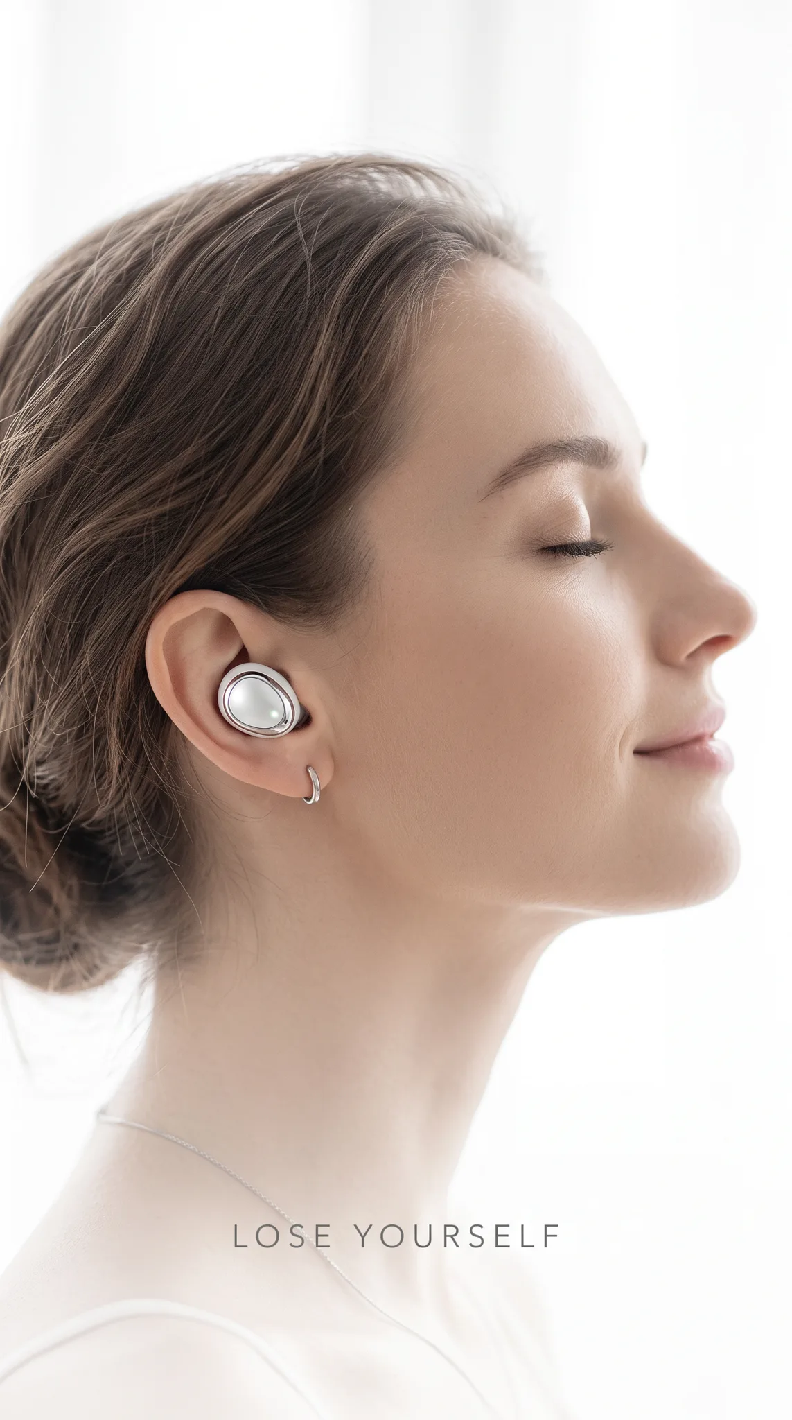 White identity frame, a serene profile in high-key light wearing the earbud