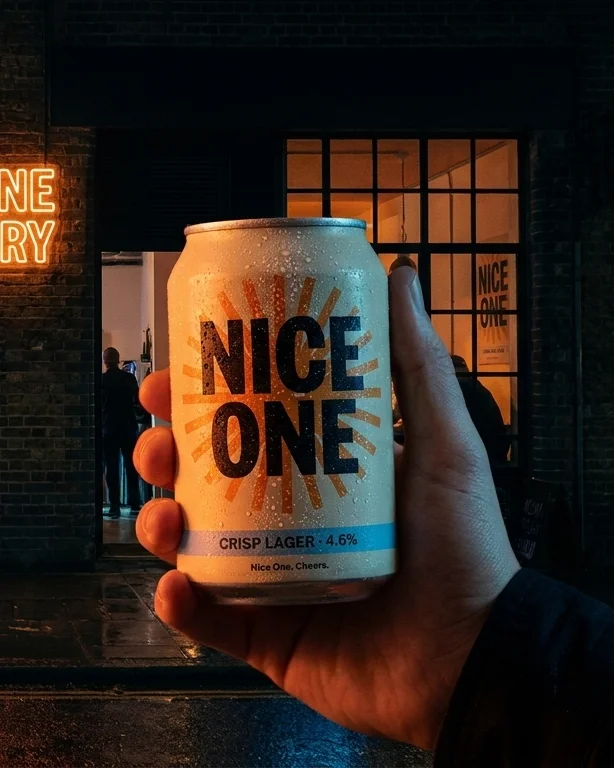A hand raising the can under the taproom neon at night