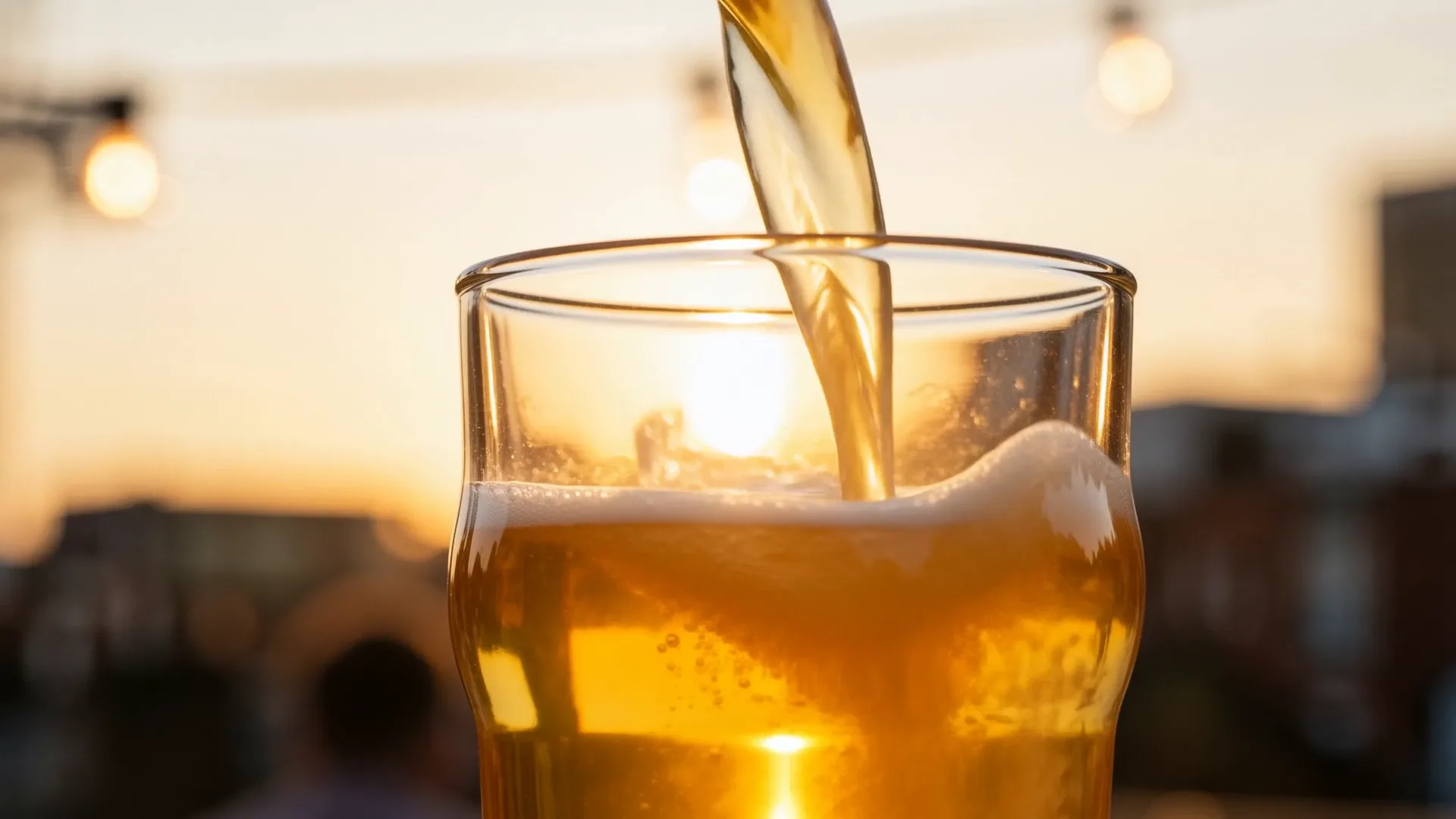 Golden lager pouring into a pint glass against a low East London sun